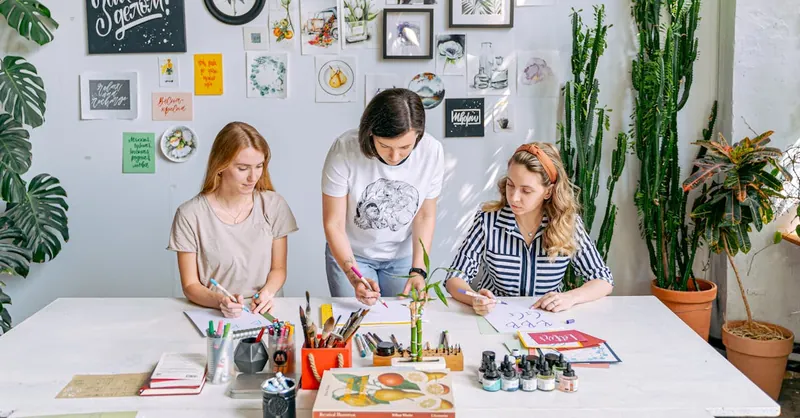 Art class scene with students and instructor working on creative projects in a bright, indoor studio.