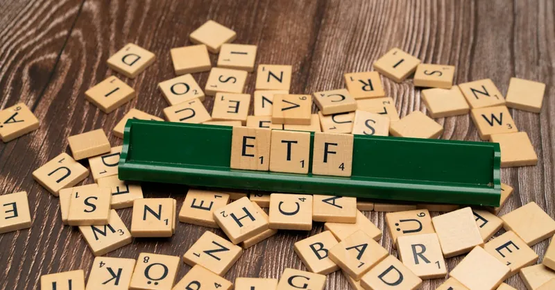 Wooden tiles spelling ETF on a game holder, representing investment themes.