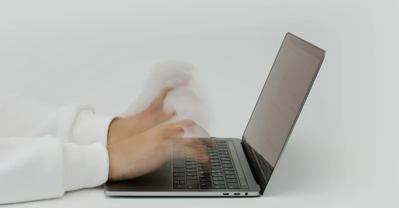 Hands rapidly typing on a laptop, illustrating speed and technology in a digital work environment.