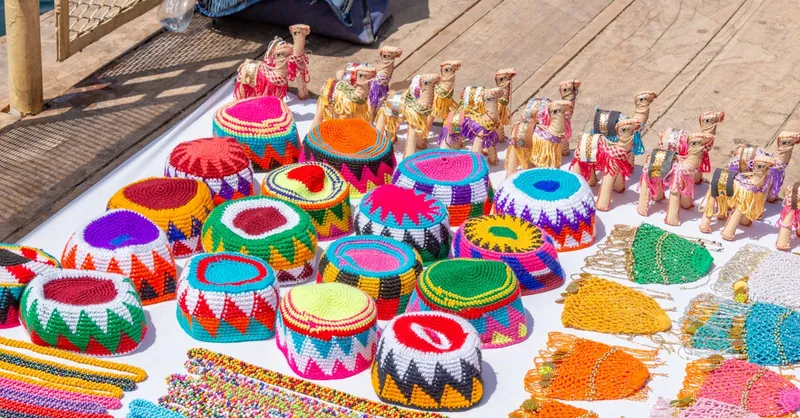 Vibrant handmade crafts and figurines arranged on a display table in an outdoor market.
