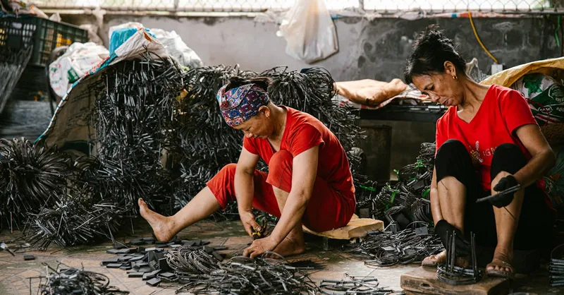 Two women crafting handmade goods in an indoor workshop, surrounded by materials.
