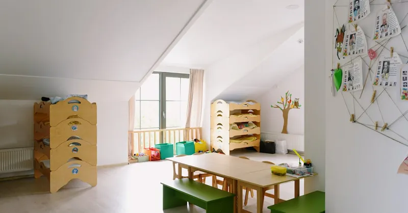 A well-lit and organized kindergarten room with wooden furniture and playful decor.