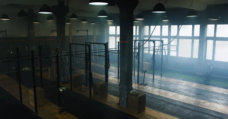 Spacious industrial-style gym interior with no people, showcasing equipment and natural light.