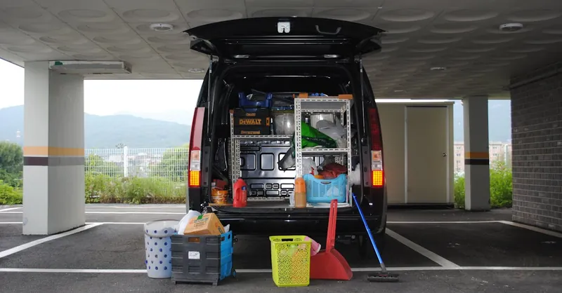 Back view of a black van with equipment in an urban parking area.