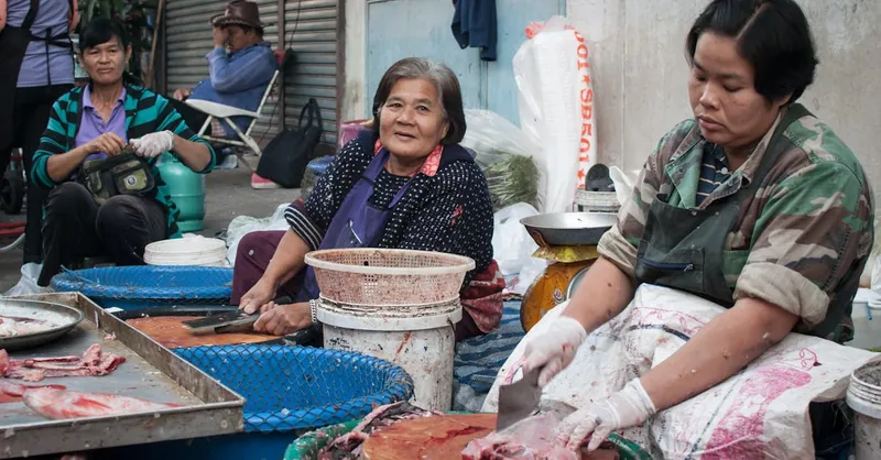 Women vendors at an urban market preparing fish for sale, showcasing local commerce.
