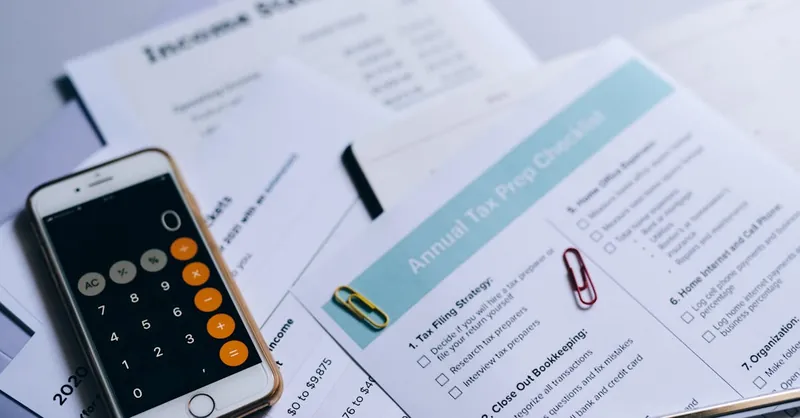 Tax preparation setup with documents, smartphone calculator, and checklist.