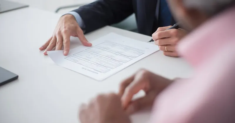 Two professionals engaging in a business meeting, signing documents for a consulting agreement.
