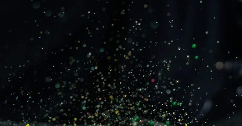 Vibrant multicolor paint splatter captured in motion with a dark backdrop, ideal for creative design.