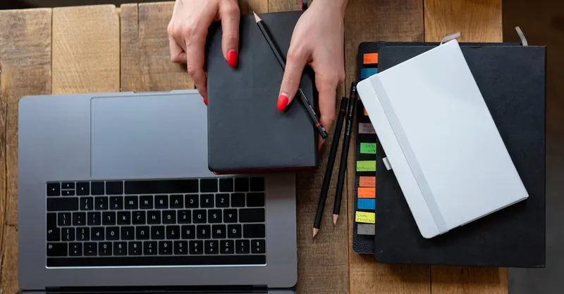 Top-down view of a desk with laptop, planner, and notebooks. Perfect for business and productivity themes.