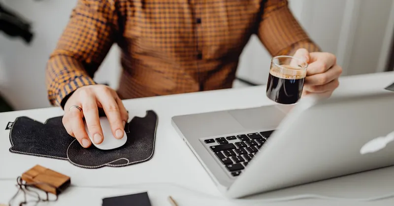A man working from home with a coffee cup and laptop, symbolizing remote work and relaxation.